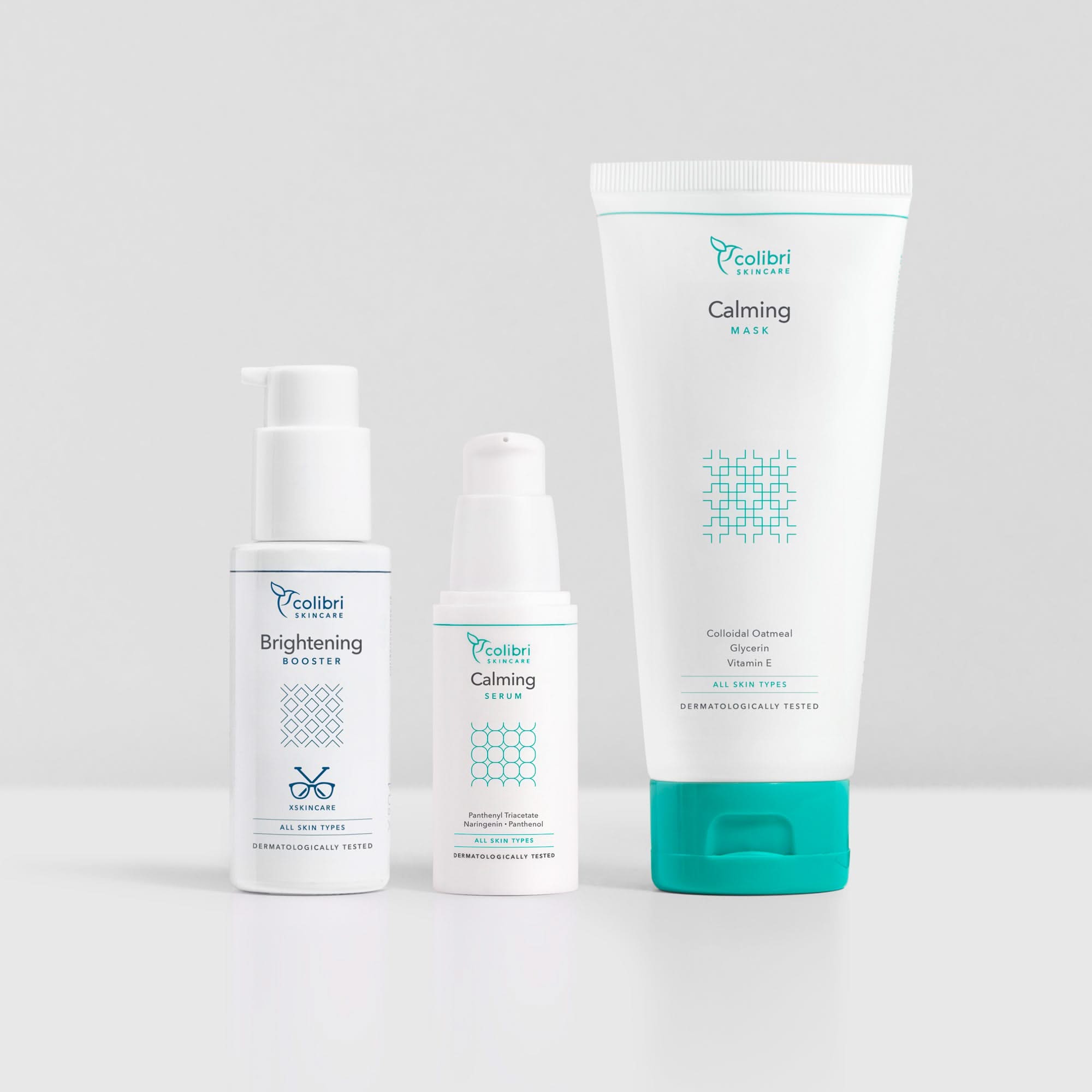 Drei weiße Colibri Skincare Produkte: ein Brightening Booster, ein Calming Serum und eine Calming Maske auf grauem Hintergrund.