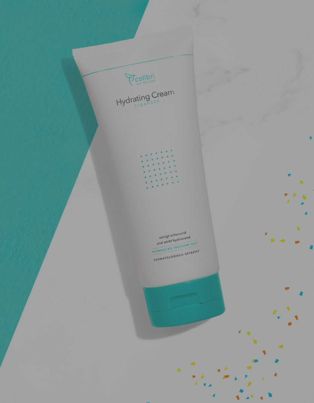 Feuchtigkeitscreme in einer Tube mit türkisfarbenem Deckel auf marmoriertem Hintergrund mit buntem Konfetti.