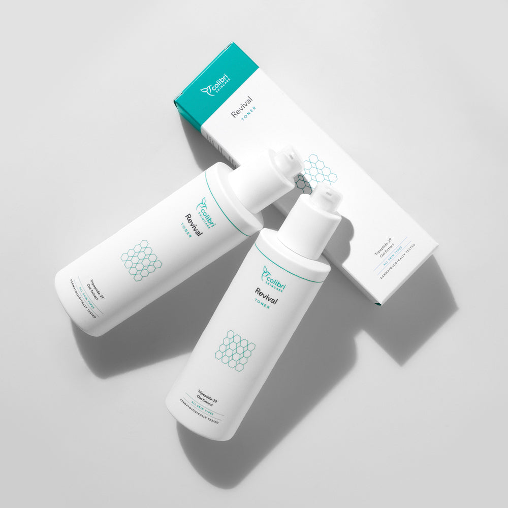 Zwei weiße Flaschen mit der Aufschrift "Revival Toner" liegen neben einer passenden Verpackung auf einem hellen Hintergrund.
