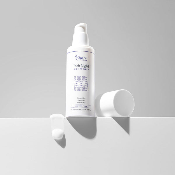Eine Flasche "Rich Night Moisturizer" steht auf einem weißen Untergrund mit etwas Creme daneben.