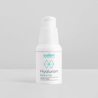 Weiße Flasche mit Hyaluron Booster von Colibri Skincare auf grauem Hintergrund.