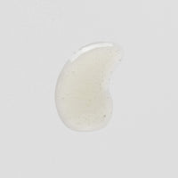 Transparenter Tropfen Gel mit kleinen Luftblasen auf weißem Hintergrund.